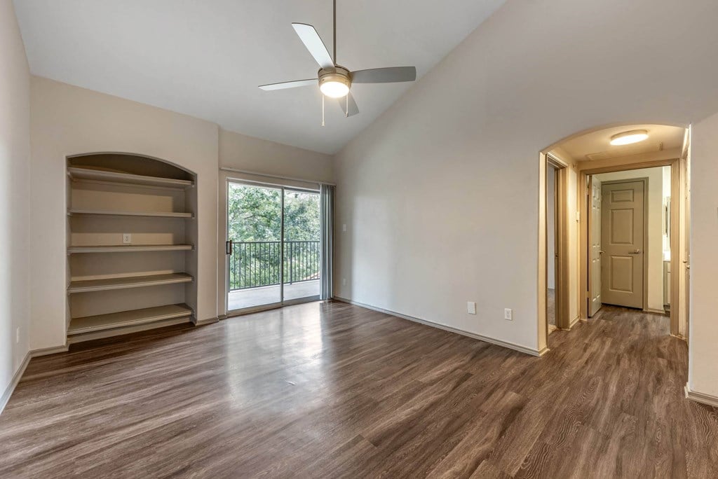an empty living room with a ceiling fan and a window